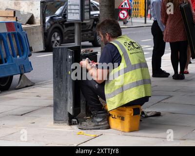 Kelly telecommunications engineer working on junction box in central London street Stock Photo