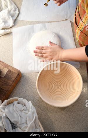 Close-up of hands preparing dough on parchment paper next to a p Stock Photo