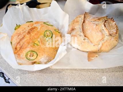 Two freshly baked loaves of bread, one with jalapeños, on parch Stock Photo