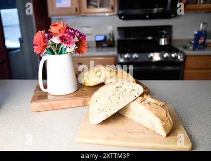 Flower vase with two loaves of bread on wooden boards in a kitc Stock Photo