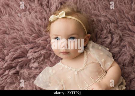 Little girl in lace dress laying on a soft rug Stock Photo