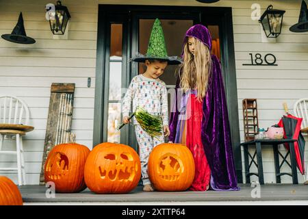 Kids in Halloween costumes on porch with carved pumpkins Stock Photo