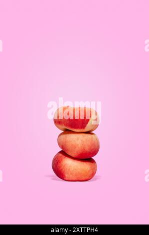 three ripe peaches on a pink background. Stock Photo