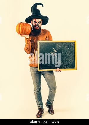 Design for Halloween banner. Make up and scary concept for man. Young man with witch hat dressed as vampire for Halloween party. Stock Photo