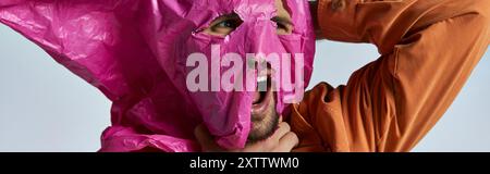 A man's face is partially covered with a pink plastic sheet. Stock Photo