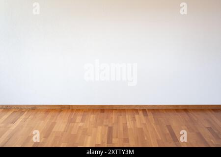 Empty apartment room with white wall and wooden parquet flooring, no people. Stock Photo