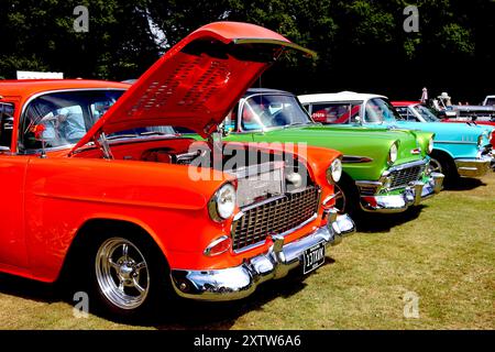 Three Tri Five Chevy Bel Airs displayed in year order; 1955 orange, 1956 green and a 1957 turquoise example at Ley Hill classic car show, August 2024. Stock Photo