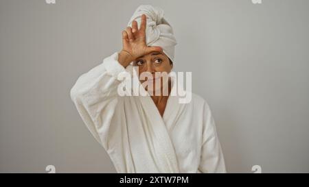 Woman in bathrobe with towel on head isolated on white background making loser gesture with hand on forehead Stock Photo