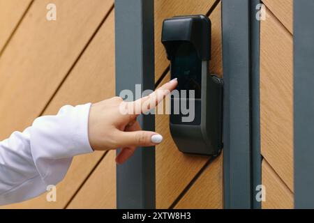 Hand Pressing Digital Door Lock on Wooden Gate Stock Photo