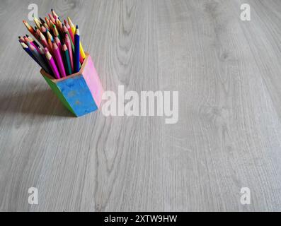 Photo of colored pencils in a pot isolated on a wooden background Stock Photo