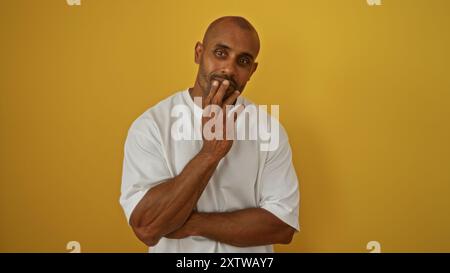 Young african american man posing against isolated yellow background, conveying thoughtful emotion Stock Photo