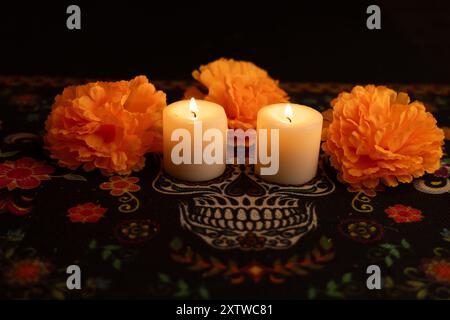 The image showcases three candles glowing warmly against a black backdrop. They are surrounded by vibrant marigold flowers and placed on a Día de los Stock Photo