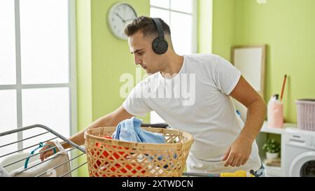 Handsome man doing laundry while listening to music in a bright, well-organized room. Stock Photo