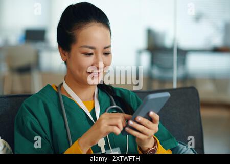 Smiling Nurse Using Smartphone in Hospital Setting Stock Photo