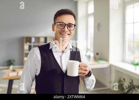 Smiling Young Businessman Enjoying Tea or Coffee Break in Office Stock Photo