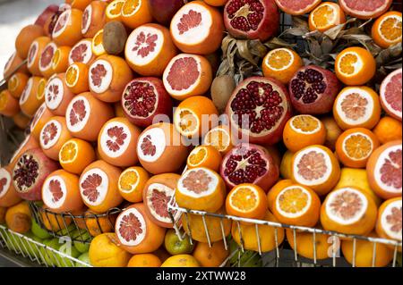 Assorted citrus fruits on display, including sliced oranges, grapefruits, and pomegranates arranged on a market stand. Stock Photo