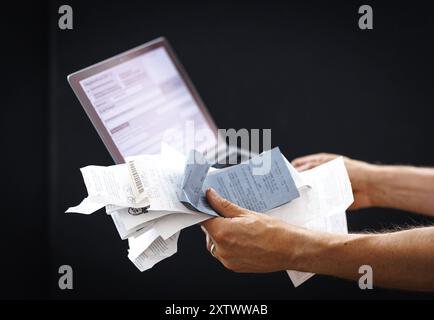 Thema Steuern. Eine Person haelt Belege und einen Laptop in Berlin, 09.08.2024. Berlin Deutschland *** Subject Taxes A person holds receipts and a lap Stock Photo
