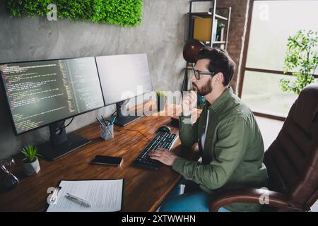 Photo of successful intelligent thoughtful man developer expert wear shirt work with operating system indoors Stock Photo