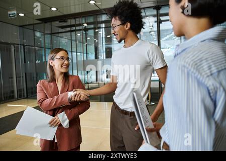 Three colleagues smile and chat in an office lobby. Stock Photo