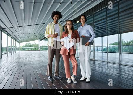 Three diverse colleagues chat and work on a rooftop terrace. Stock Photo