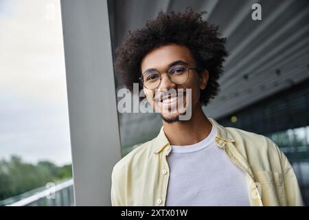 A young man with glasses smiles at the camera while standing on a rooftop. Stock Photo