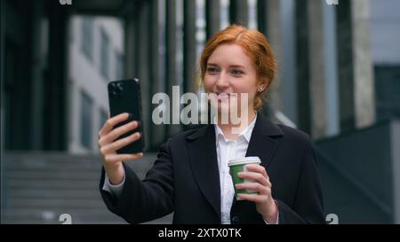 Successful smiling Caucasian ginger girl businesswoman lady female woman student worker talking speak tell online phone gadget mobile meeting Stock Photo
