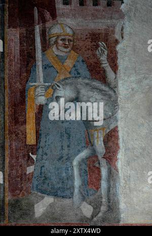 Rider on grey horse raises right hand in blessing and a soldier, guard or clergyman stands with his broadsword raised, outside a battlemented castle or fortress. Damaged fresco in the cathedral at Bolzano, South Tyrol, Trentino-Alto Adige, Italy, the chiefly Gothic Duomo di Santa Maria Assunta (Cathedral of the Assumption of Our Lady). One of the frescoes in the cathedral illustrating the evolution of  figurative art from the early 1300s AD Gothic linear style to the early 1400s AD. Stock Photo