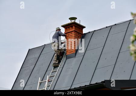 Traditional manual method of cleaning the chimney on the roof Stock Photo