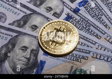 One Bitcoin on hundred dollars bills. Closeup, macro shot Stock Photo