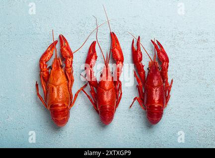 Three whole cooked crawfish lying on blue background top view Stock Photo