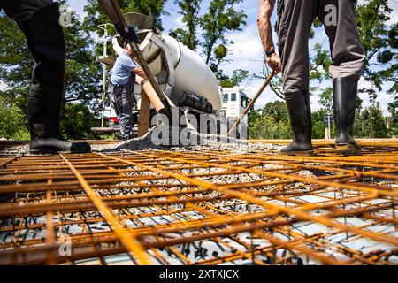 Concrete Pouring onto Rebar Framework for Ground Slab Construction Stock Photo