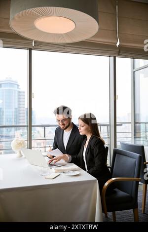 Two partners sitting in the restaurant working with laptop and documents Stock Photo