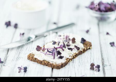 Slice of wholemeal bread with fresh cutted cress and cream cheese on an old wooden table (selective focus, close-up shot) Stock Photo