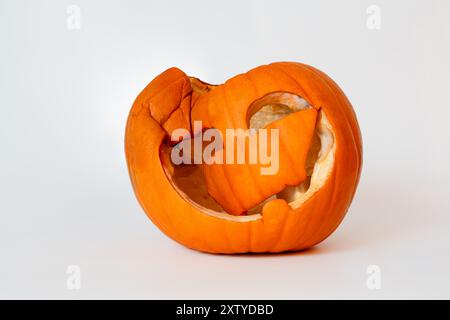 A collapsed and decayed Jack-o'-lantern with a broken face sits on a white background, showing signs of aging Stock Photo