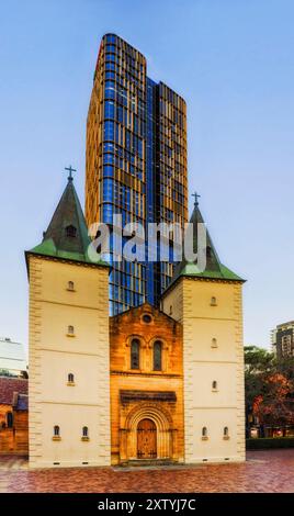 Tall straight spectacular historic heritage St John's cathedral in the city of Parramatta next to modern high-rise apartment office building. Stock Photo