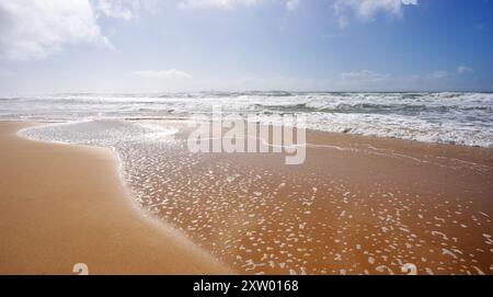 Seascape showing crashing waves from rough surf rolling onto the wet sand following days of bad weather along the coastline on the Sunshine Coast, Kaw Stock Photo