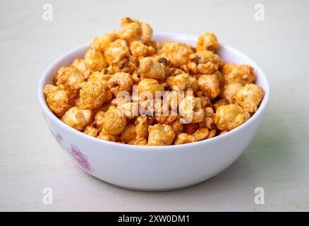 Bowl of barbecue flavored popcorn on light wooden background. Stock Photo