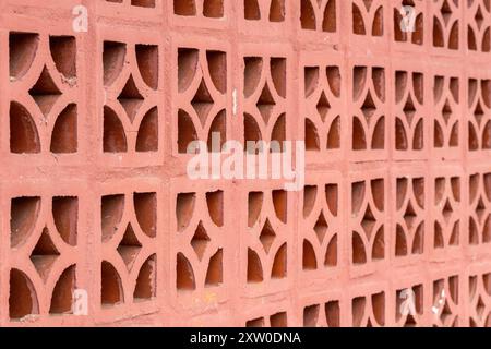 Repeating diamond pattern in red brick. Abstract background. Close-up of aesthetic red clay bricks wall with ventilation holes. Stock Photo