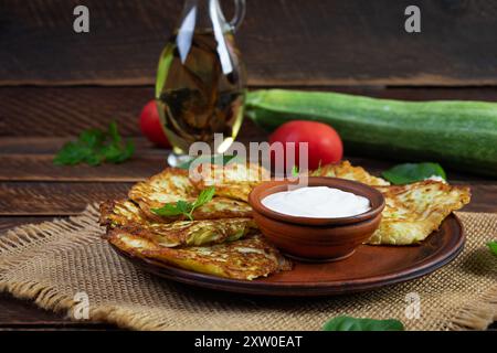 Zucchini fritters on a plate with sour cream. Delicious zucchini patties Stock Photo