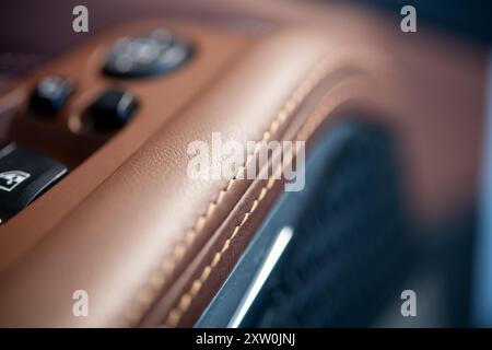 Detailed view of rich brown leather upholstery in a luxury car, featuring meticulous stitching and sleek controls, emphasizing craftsmanship and elega Stock Photo