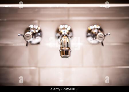 Stylish chrome faucet positioned centrally above a pristine white sink, featuring multiple handles for temperature control in a chic bathroom environm Stock Photo