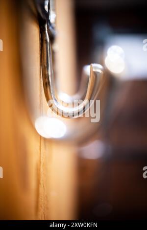 A close-up view of shiny metal hooks mounted on a wooden wall, perfect for hanging coats, bags, or accessories, enhancing both functionality and aesth Stock Photo