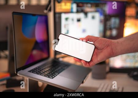 Smartphone blank screen mockup. Office interior. Laptop with external monitors equipment. Stock Photo