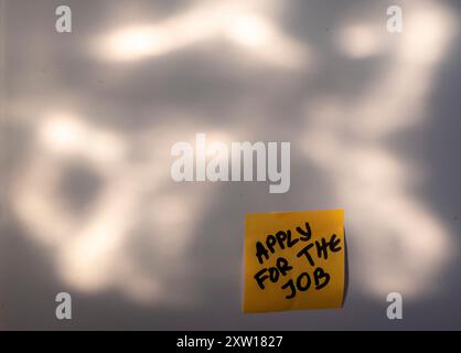 Daily Reminder: Apply for the Job - A Yellow Sticky Note in Sunlight. Sunset frame. Stock Photo