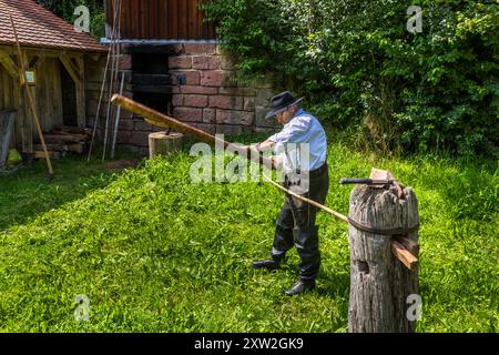 Raftsman Martin Spreng turns a heated pine trunk in the so-called "Wiedstock" at the Monhardter Wasserstube near Altensteig, Baden-Württemberg, Germany. A turning rod separates the wood fibres, forming a kind of wooden rope, the "Wiede". Rafting has been recognised as UNESCO intangible cultural heritage since 2022. Stock Photo