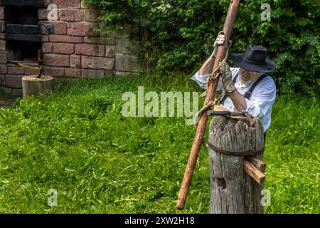 Raftsman Martin Spreng turns a heated trunk in the Wiedstock at the Monhardter Wasserstube near Altensteig, Baden-Württemberg, Germany. The turning rod separates the wood fibres, forming a "Wiede" – a wooden rope used to bind rafts. Rafting has been recognised as UNESCO intangible cultural heritage since 2022. Stock Photo