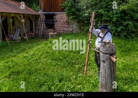 Raftsman Martin Spreng turns a heated trunk in the Wiedstock at the Monhardter Wasserstube near Altensteig, Baden-Württemberg, Germany. The turning rod separates the wood fibres, forming a "Wiede" – a wooden rope used to bind rafts. Rafting has been recognised as UNESCO intangible cultural heritage since 2022. Stock Photo
