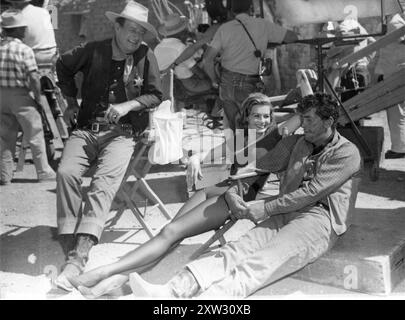 JOHN WAYNE, ANGIE DICKINSON and DEAN MARTIN relaxing between scenes on location for RIO BRAVO 1959 Director HOWARD HAWKS Story B.H. McCAMPBELL Screenplay JULES FURTHMAN and LEIGH BRACKETT Costume Design MARJORIE BEST Music DIMITRI TIOMKIN Produced by HOWARD HAWKS Warner Bros. /Armada Productions Stock Photo