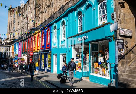 Tourists with wheeled carry on luggage walking on Victoria Street, Edinburgh, Scotland, UK Stock Photo