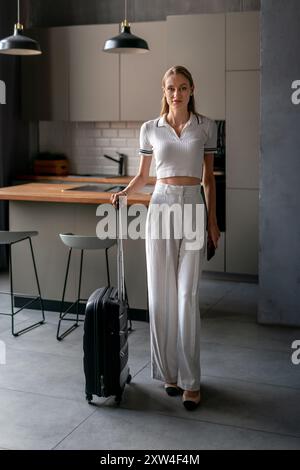 Young woman with suitcase in rented apartment. Travel booking and accommodation Stock Photo